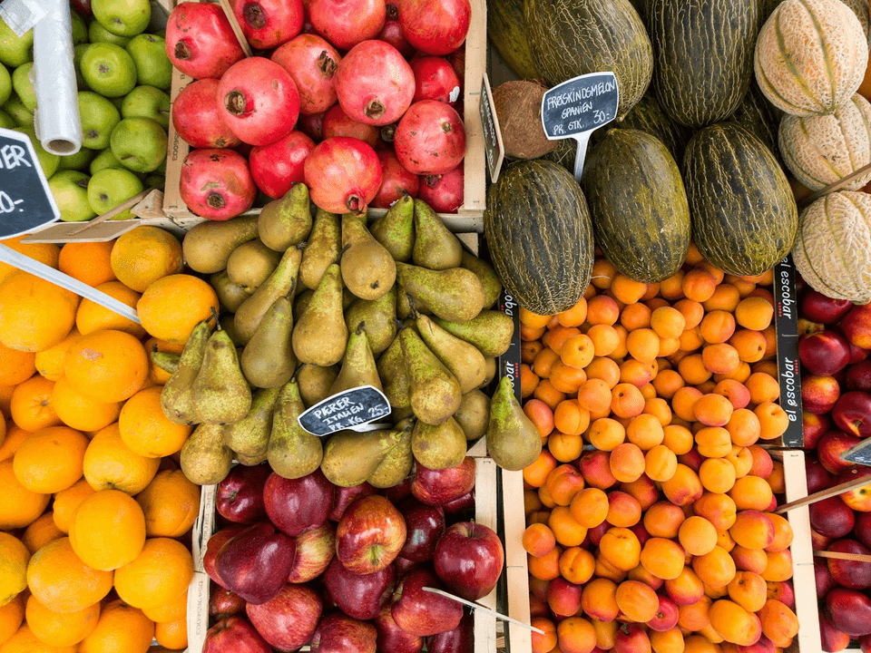 Puesto de frutas visto desde arriba. Un recuadro de color marca cada tipo de fruta con su nombre.